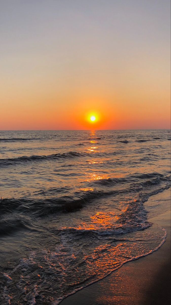 the sun is setting over the water at the beach