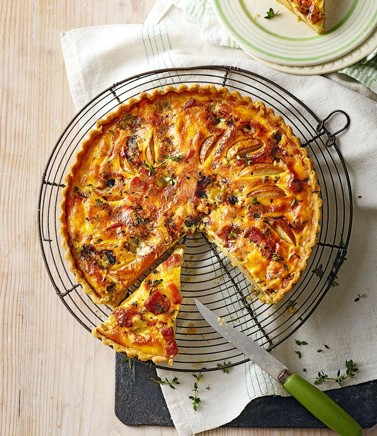 a pizza sitting on top of a metal rack next to a knife and plate with a slice missing