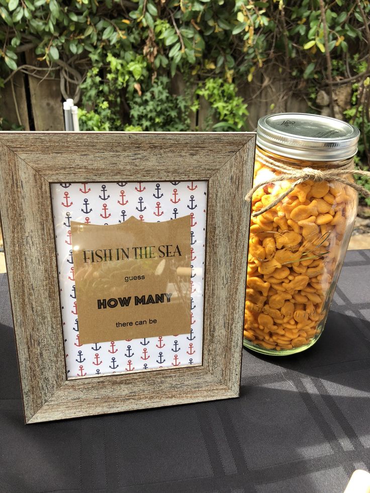 a mason jar filled with fish in the sea crackers next to a framed sign