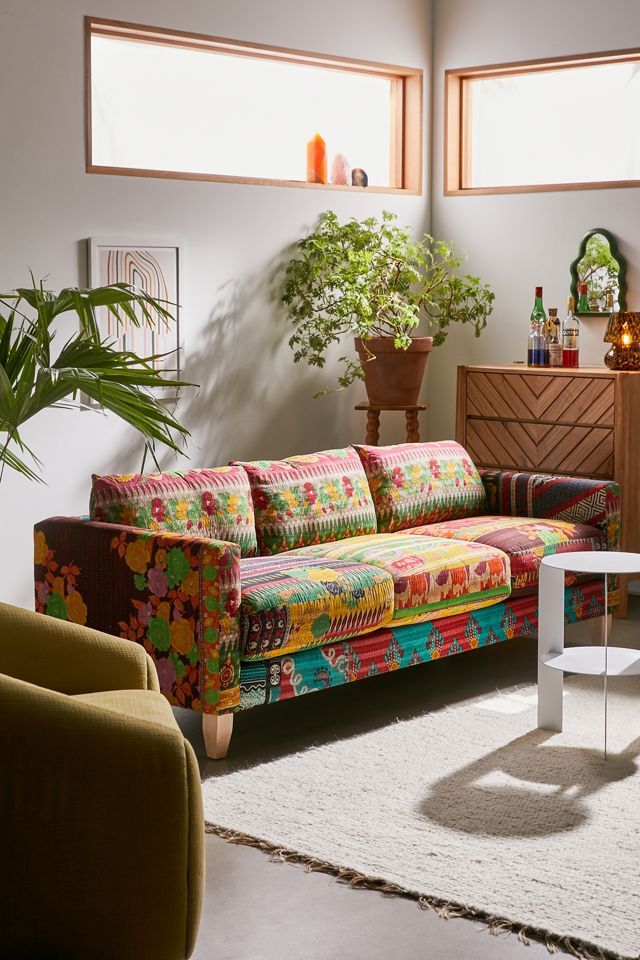 a brightly colored couch and chair in a living room with potted plants on the wall