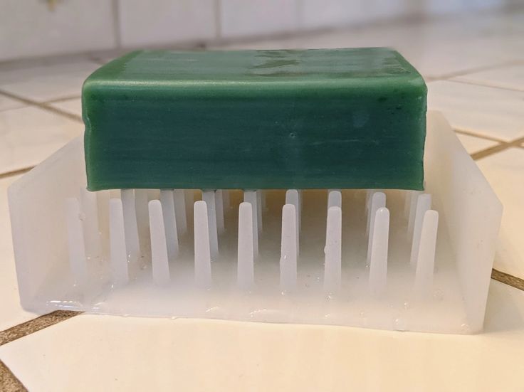 a green and white tooth brush sitting on top of a tiled floor