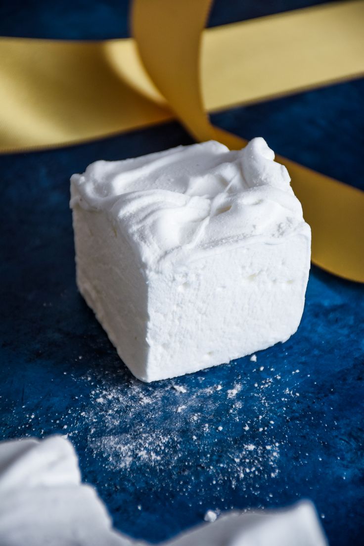 a piece of white cake sitting on top of a blue table next to a yellow ribbon