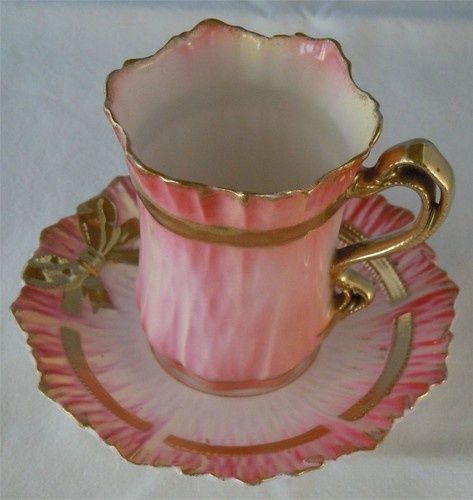 a pink cup and saucer with gold trim