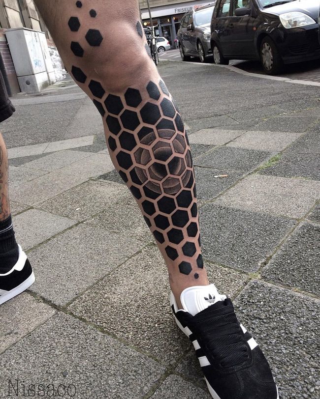 a man's leg with black and grey honeycombs tattoo on the legs