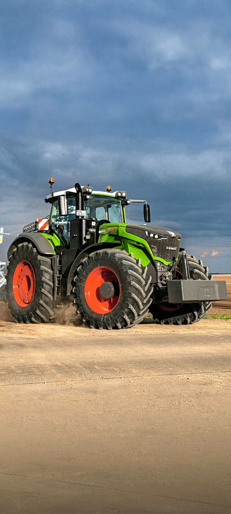 a tractor is driving down a dirt road with it's loader on its back