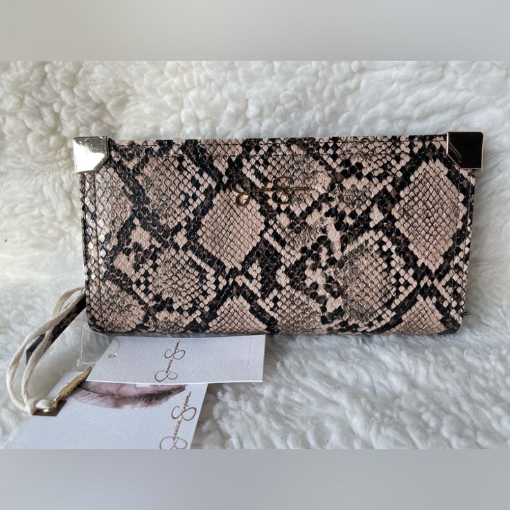 a snake skin purse sitting on top of a white furnishce covered floor next to a pair of scissors