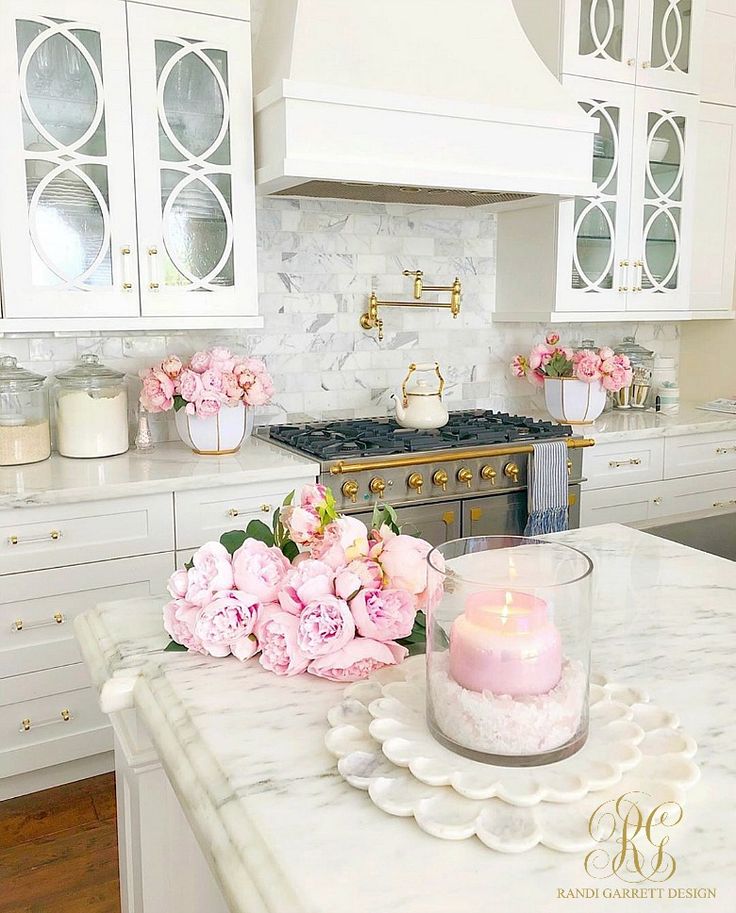 a pink candle sitting on top of a counter next to a vase filled with flowers