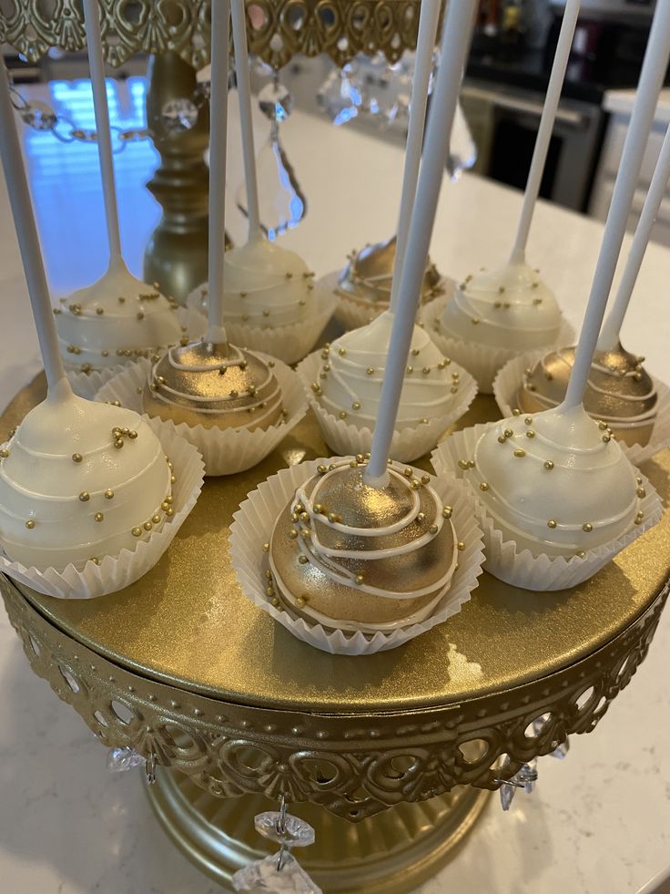 some white and gold desserts are on a tray with candles in them for decoration