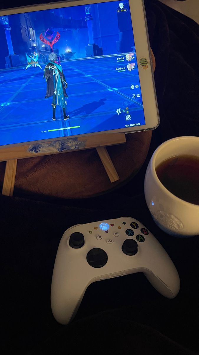 a video game controller sitting next to a cup of coffee and an ipad on a table