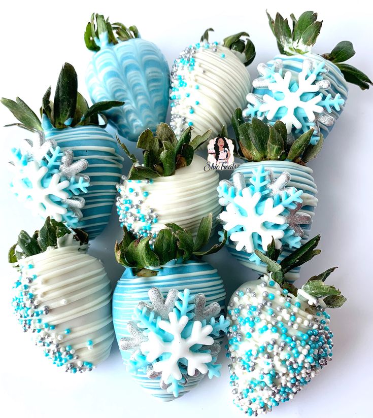 blue and white decorated strawberries with snowflakes on them are arranged in a pile