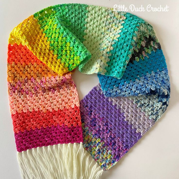 a multicolored crocheted scarf with fringes on the bottom and sides