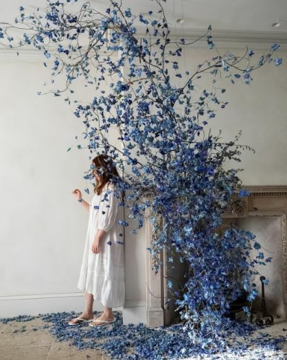 a woman standing in front of a blue tree