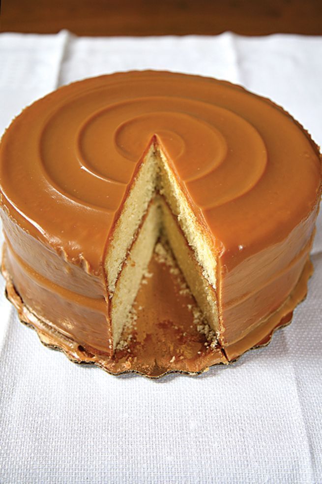 a cake with a slice cut out of it sitting on a white cloth covered table