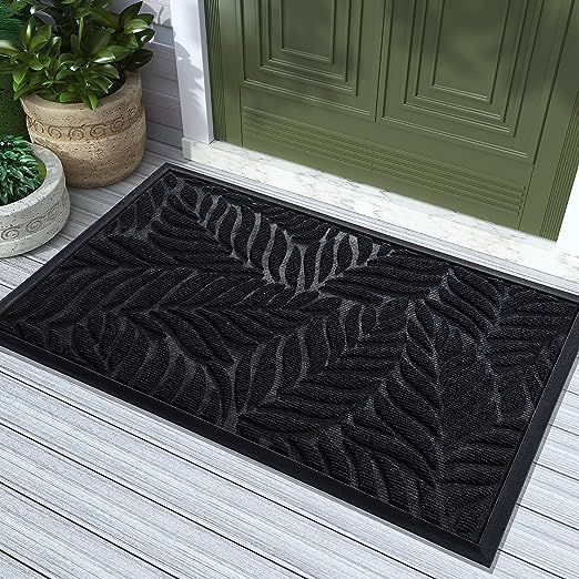 a black door mat sitting on top of a wooden floor next to potted plants