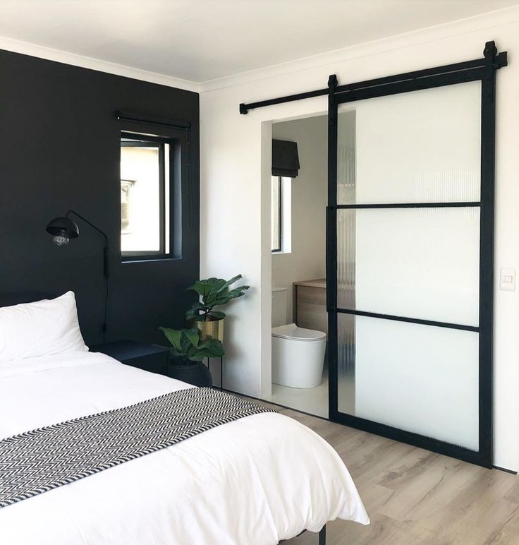 a bedroom with black walls and white bedding