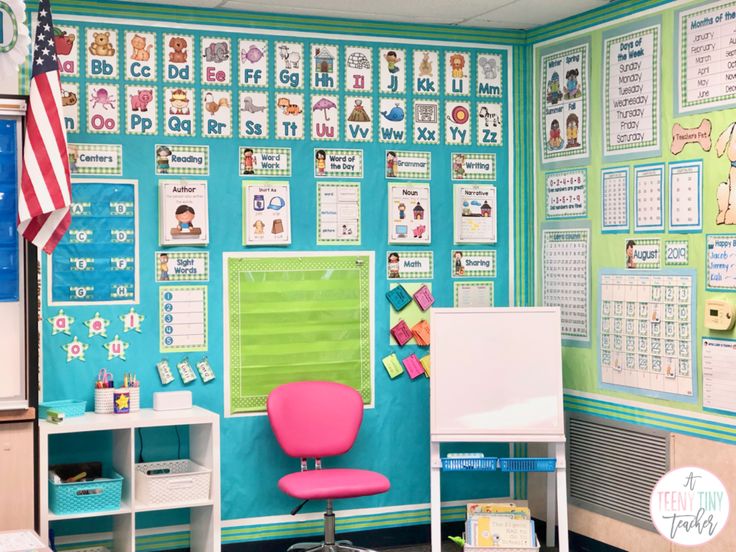 a classroom with a desk, chair and calendars on the wall in front of it