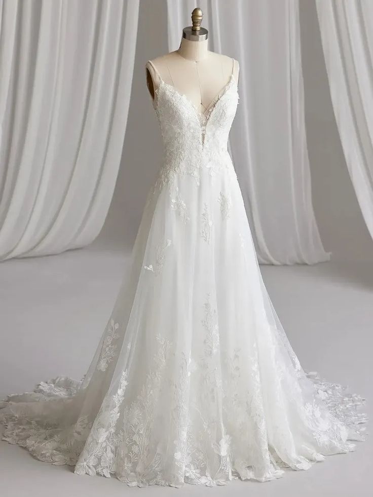 a white wedding dress on a mannequin in front of curtained drapes