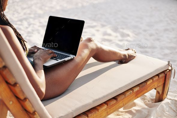 a woman sitting in a beach chair using her laptop computer - stock photo - images