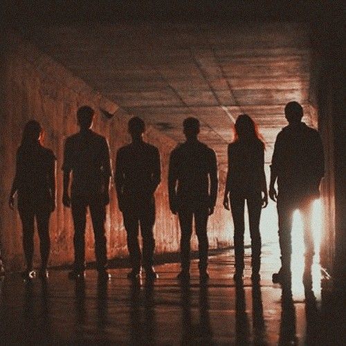 group of people standing in front of a light at the end of a dark tunnel