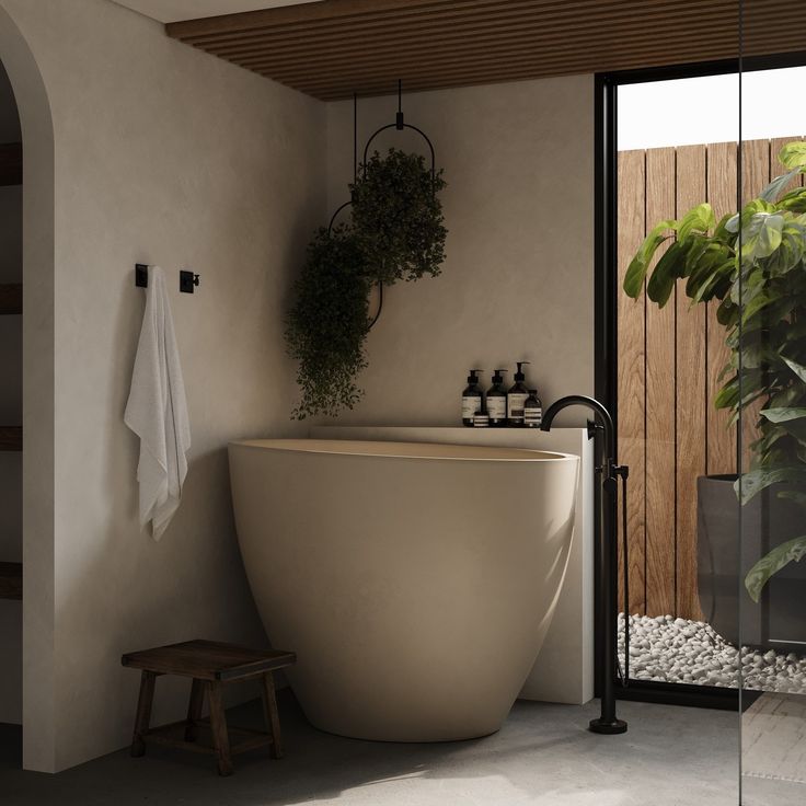 a bath tub sitting next to a wooden bench in a bathroom with plants on the wall