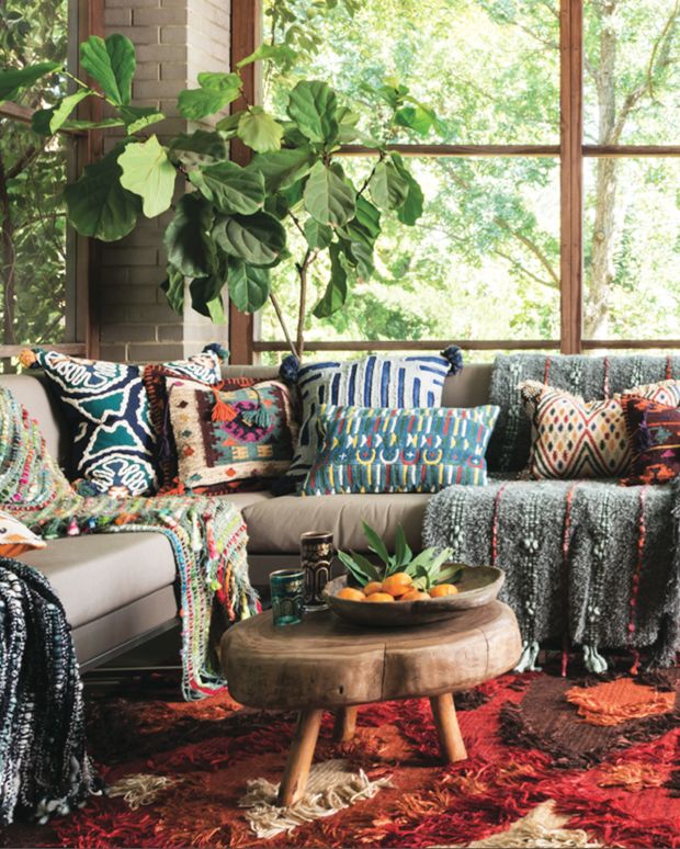 a living room filled with lots of furniture and plants on top of a red rug