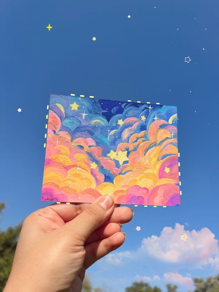 someone is holding up a piece of art that looks like clouds and stars in the sky