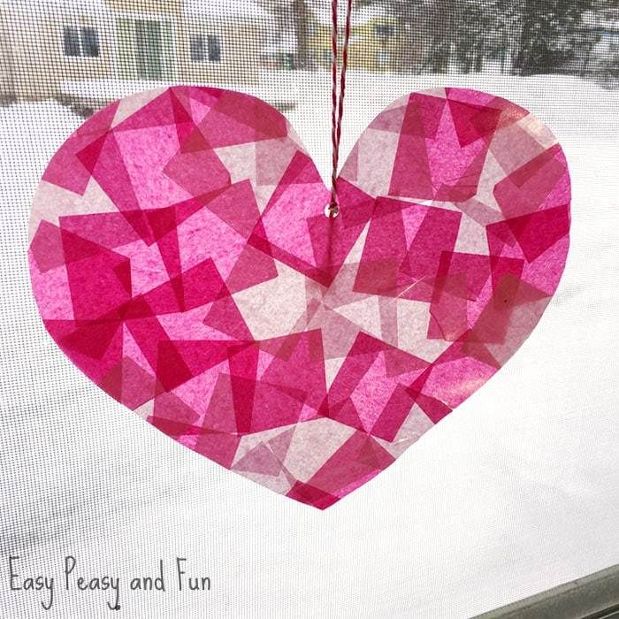 a pink heart hanging from a window in the snow