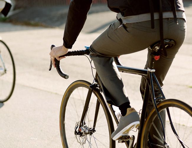 a man riding a bike down the street with his helmet strapped to it's handlebars