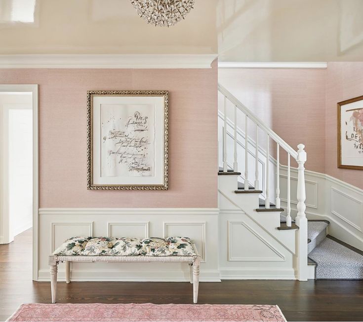 the entryway is decorated in pale pinks and white with an ornate chandelier