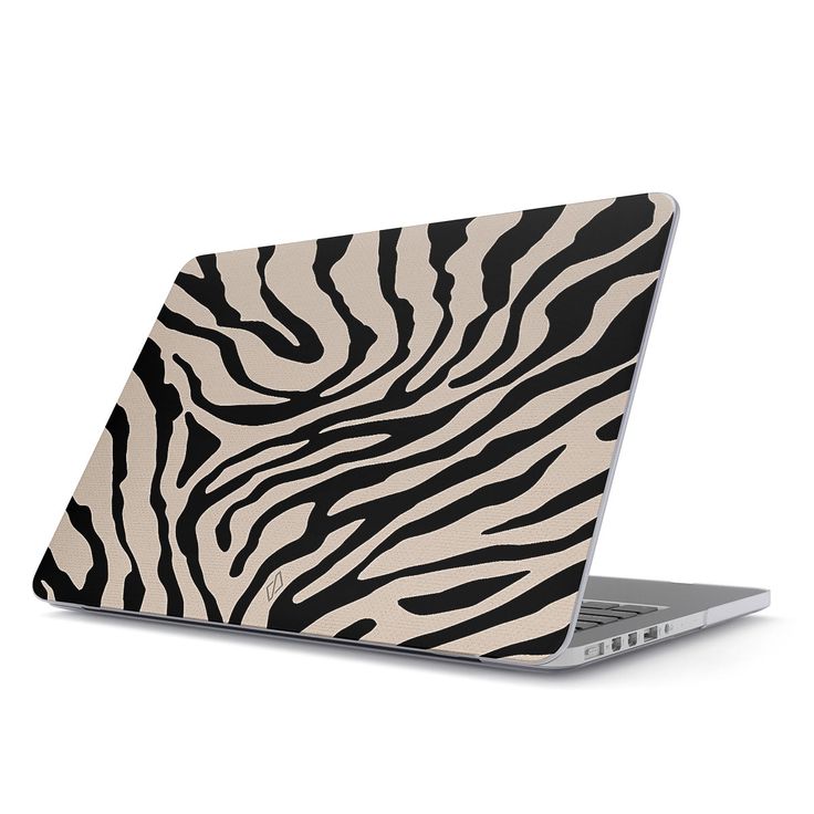 an open laptop computer sitting on top of a white surface with black and white zebra print