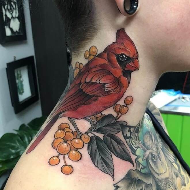 a woman's neck with a red bird and berries tattoo on her left side