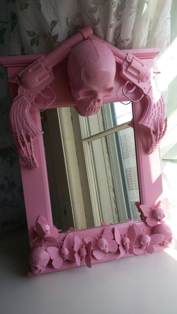 a pink mirror sitting on top of a table next to a wallpapered window