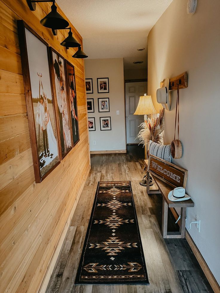 a hallway with wood paneling and pictures hanging on the wall next to a bench