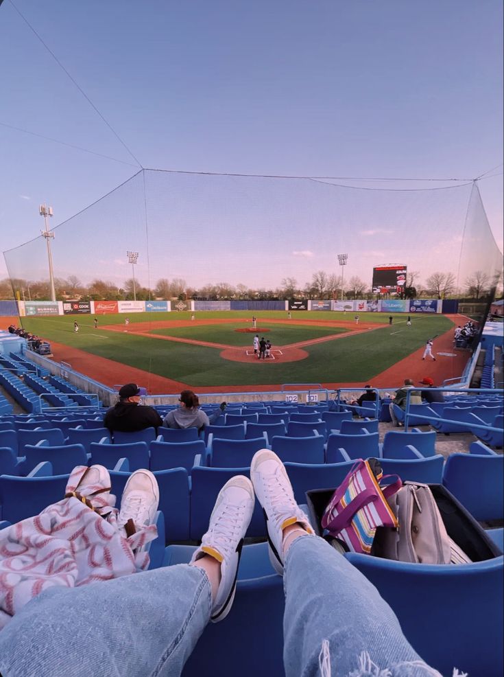 someone is sitting in the bleachers at a baseball game with their feet up