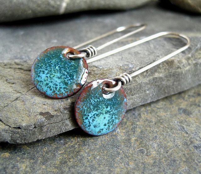 two blue and brown earrings sitting on top of a rock