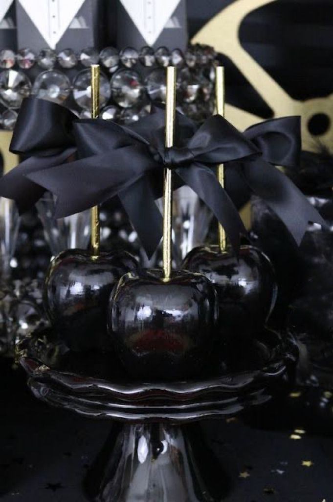 black and gold apples with bows on display in front of other decorative items at a party