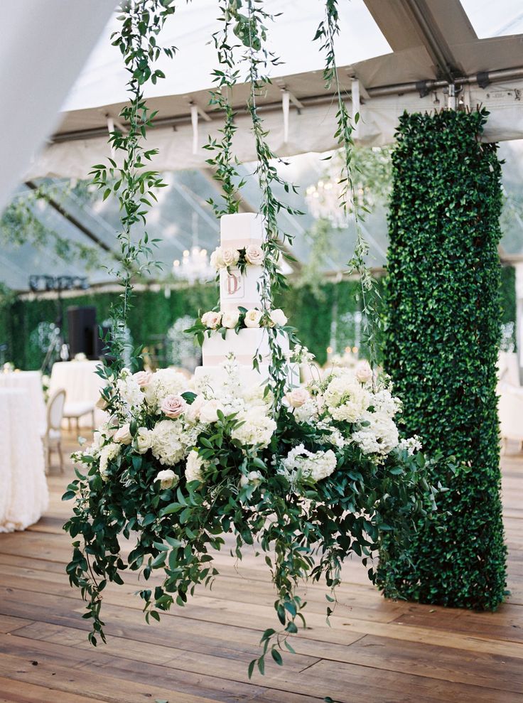 a wedding cake sitting on top of a table covered in white flowers and greenery