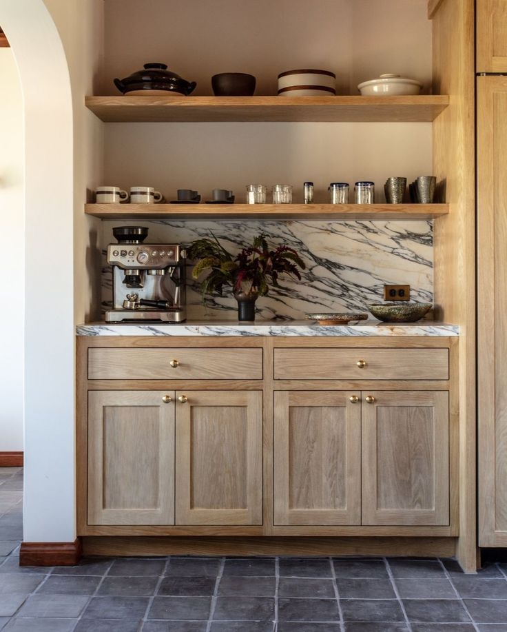 a kitchen with wooden cabinets and marble counter tops in the center, along with open shelving