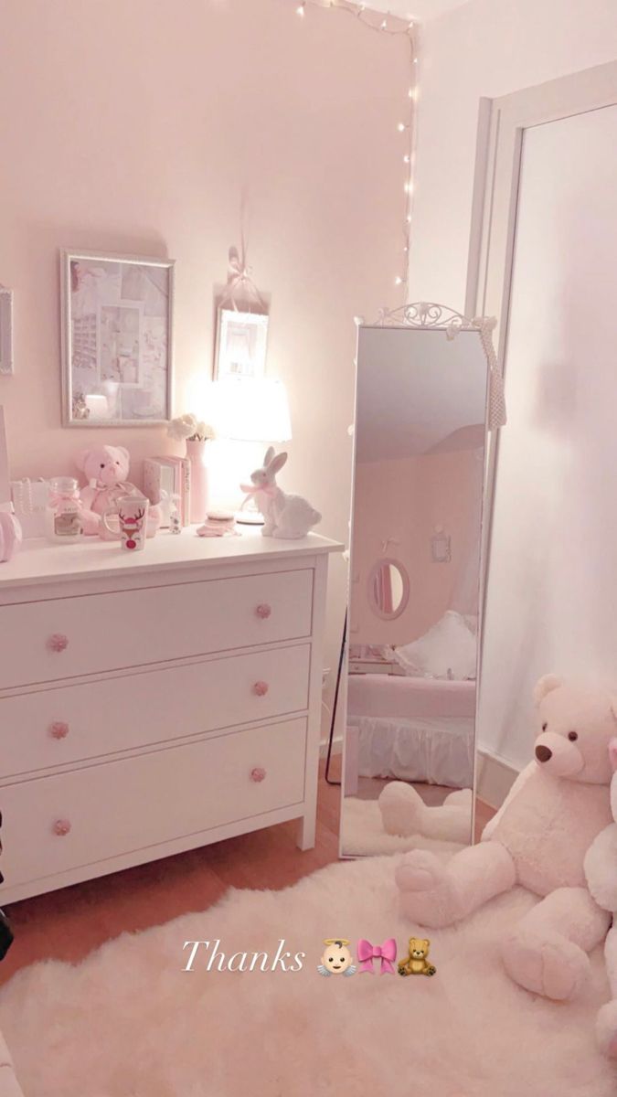 there is a teddy bear sitting on the floor in front of a dresser and mirror