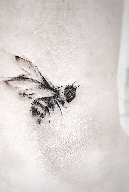 a black and white photo of a bee on the side of a woman's stomach