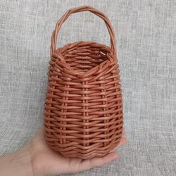 a hand holding a brown wicker basket