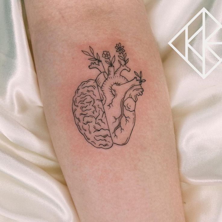 a heart and brain tattoo on the left arm, with flowers growing out of it