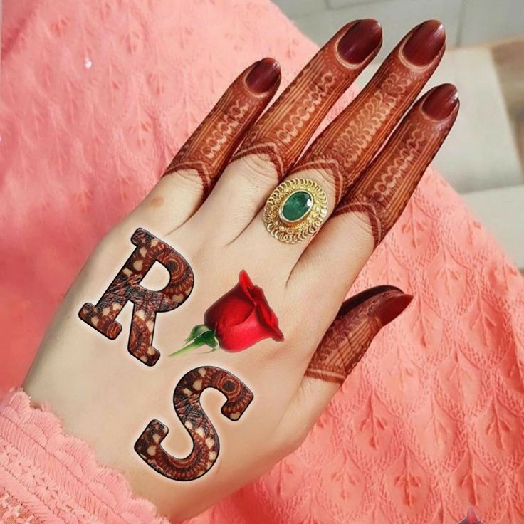 a woman's hand with hennap and ring on it, holding a rose