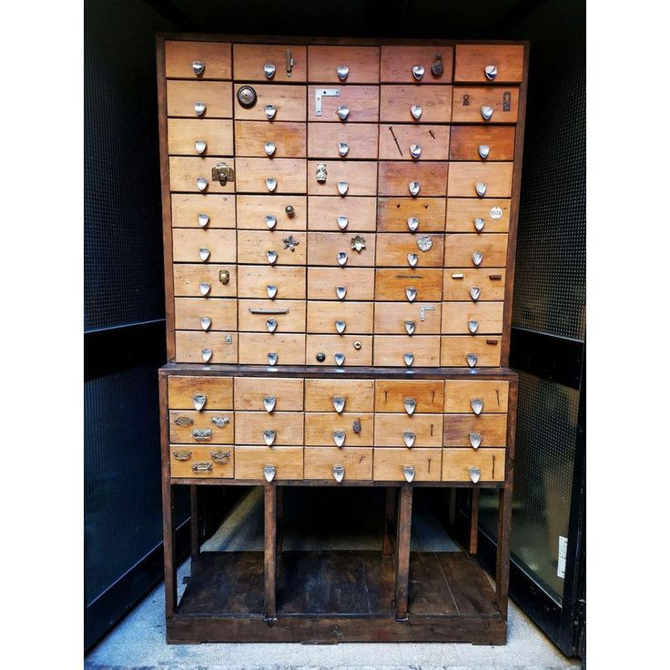 an old wooden cabinet with lots of drawers and knobs on the front, sitting in a storage area