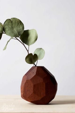 a wooden vase with some green leaves in it