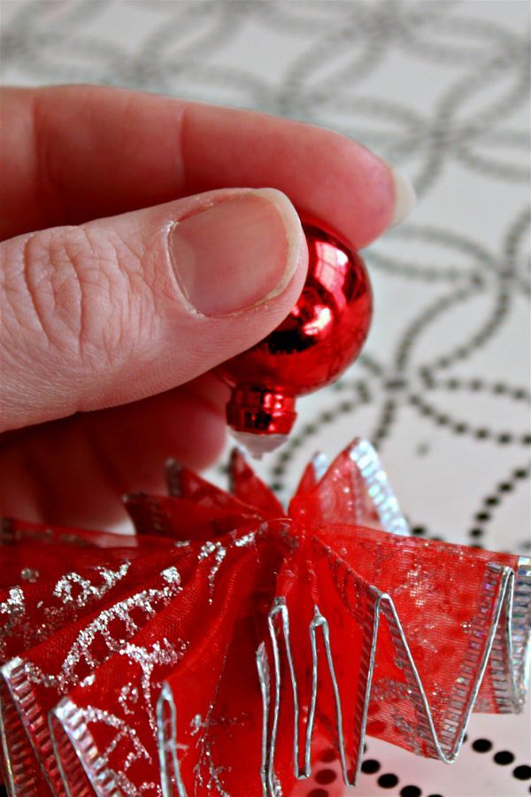 a hand is holding a red ornament