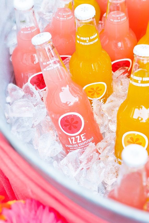 there are many bottles of orange juice in the ice bucket with pink flowers on the table