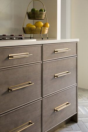 a kitchen counter with drawers and fruit on top