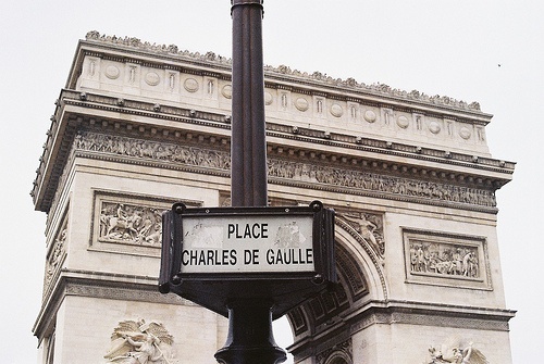 a street sign in front of the arc de trioe, which is located on the corner of rue charles de cauille