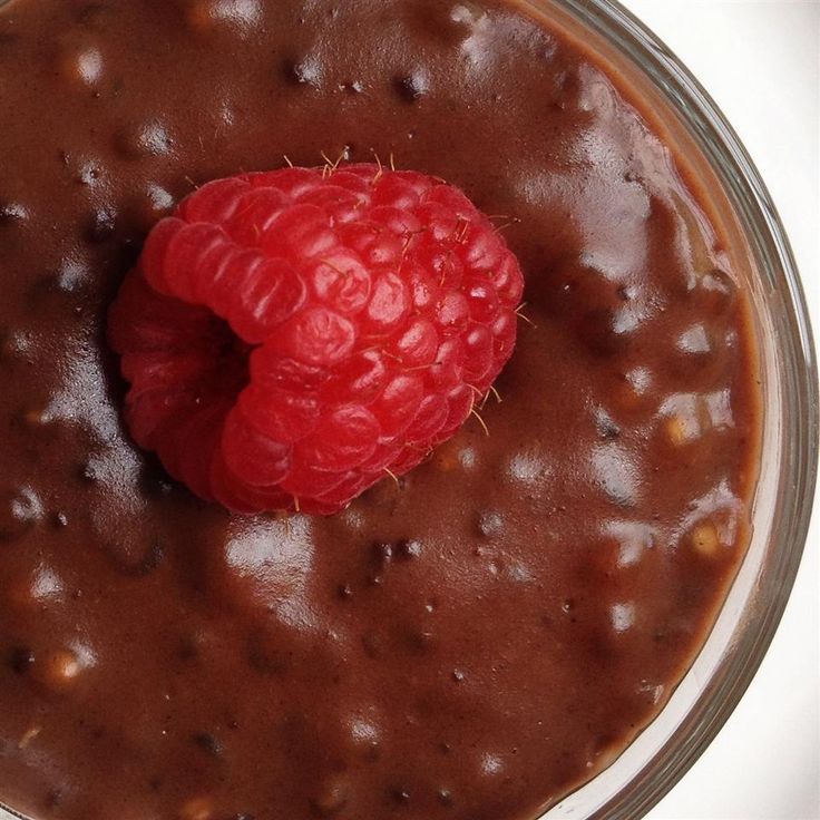 a bowl filled with chocolate pudding and a raspberry on top